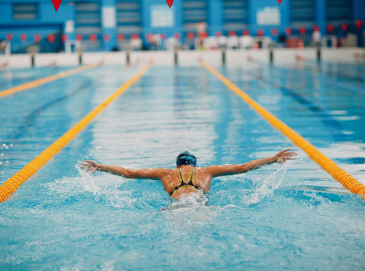 There is a woman swimming in a pool with lanes.