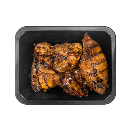 Grilled chicken pieces on a black tray